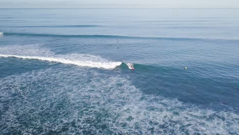 Surfers-riding-hard-waves-at-waikiki-beach-in-honolulu-hawaii-on-a-clear-sky-day,-AERIAL-DOLLY