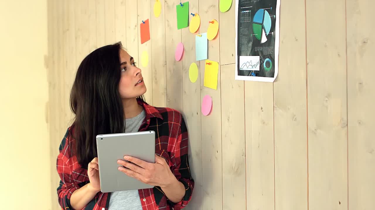 ejecutivo de negocios usando una tableta digital mientras lee un aviso en la pared