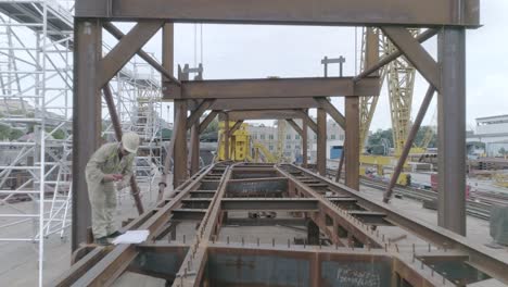 construction workers in blue working on the large steel base for a bridge