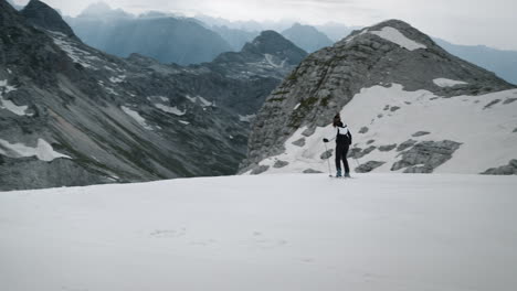 Eine-Frau-Fährt-Auf-Dem-Verschneiten-Hang-Auf-Den-Wanderer-Zu-Und-Bleibt-Stehen