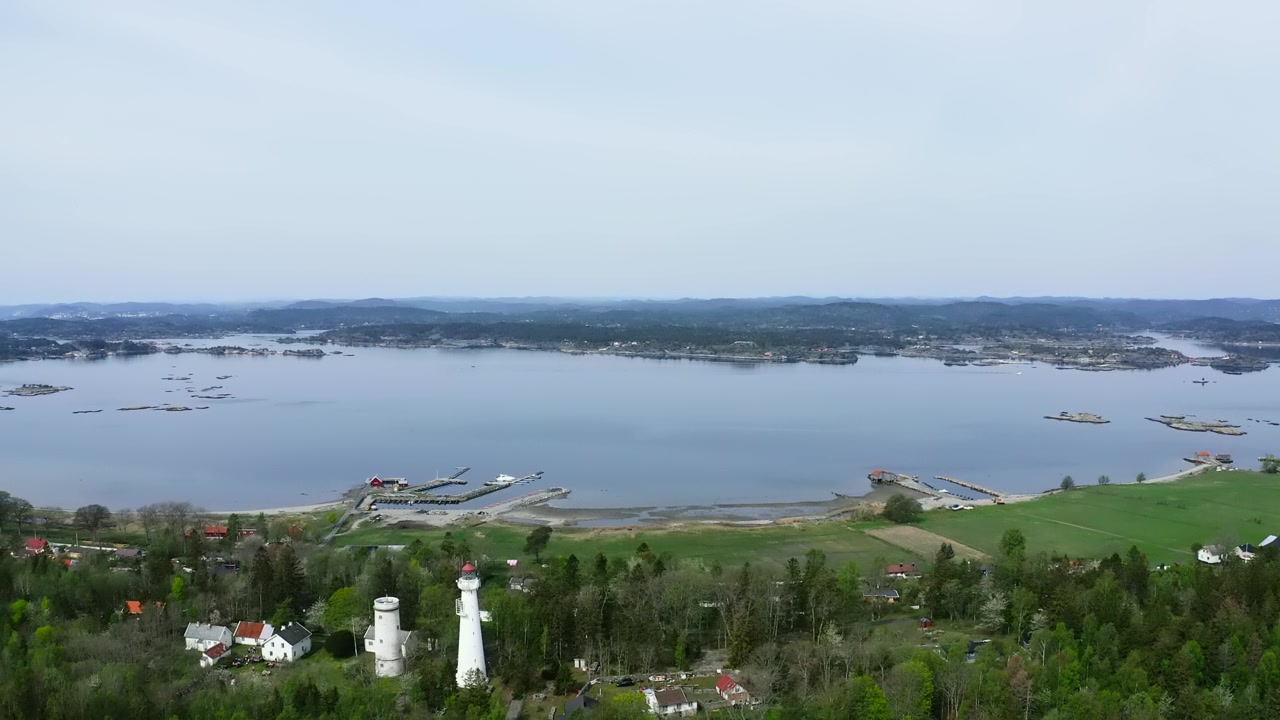 Veduta aerea di un faro su una penisola boscosa circondata dall'acqua.