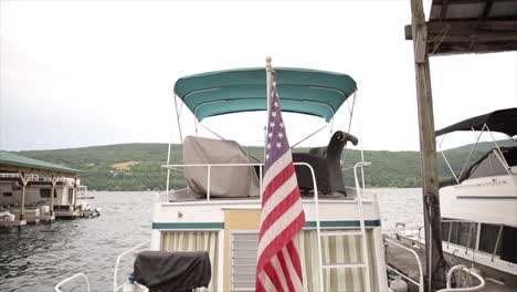 american flag waving in the wind on the stern of a yacht docked at a marina on a lake