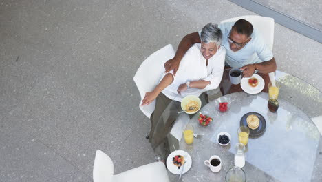 pareja biracial disfruta de un desayuno saludable juntos, con una vista de arriba hacia abajo con espacio para copiar