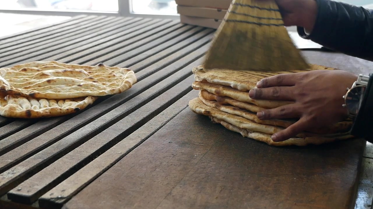Baker som rengjør nybakt flatbrød med en liten kost.
