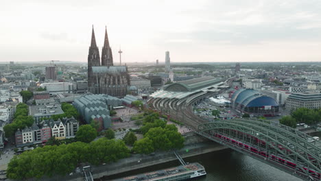 drone films the cologne cathedral, the cologne central station, the cologne theather in the sunset, the drone moves down and the rhine with the hohenzoller bridge comes into the picture