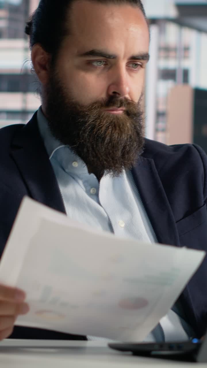 Video verticale. Uomo d'affari adulto che conduce analisi di report con documenti e approfondimenti
