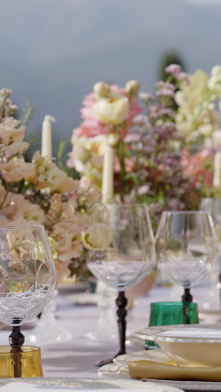 Elegante allestimento della tavola all'aperto con centrotavola floreali e bicchieri di cristallo.