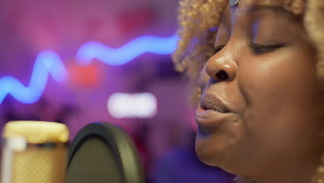 woman singing into a microphone in recording studio