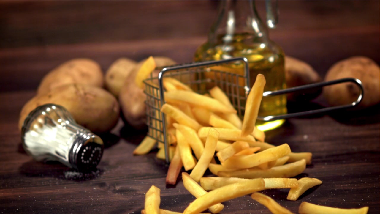 Patatas Fritas Crujientes Cayendo de una Mini Cesta sobre una Mesa de Madera Rústica