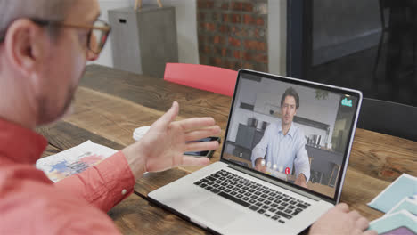 un hombre de negocios caucásico en una llamada de video con un colega caucásica en la pantalla.