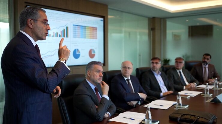 Corporate Manager Presenting Business Performance Charts To Executive Team In Boardroom