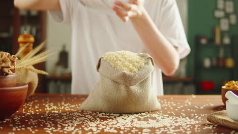 person pouring rice grains into a burlap sack