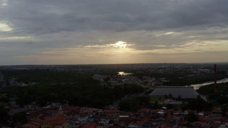 Rising-aerial-drone-shot-of-a-small-historic-neighborhood-road-in-the-old-downtown-of-the-coastal-capital-city-of-Joao-Pessoa,-Paraiba,-Brazil-with-homes,-churches-and-factories-during-sunset