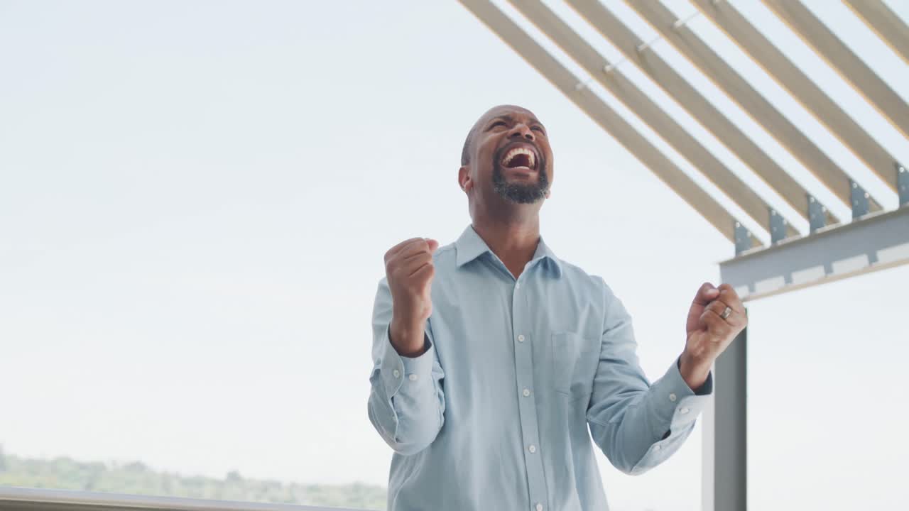 Happy african american businessman celebrating at office, slow motion