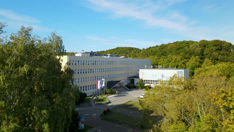 toma aérea de un dron de la fachada del edificio de la universidad moderna con árboles soleados
