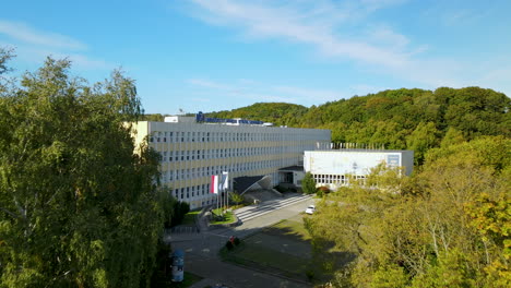 aerial dolly forward drone shot of modern university building facade with sunny trees