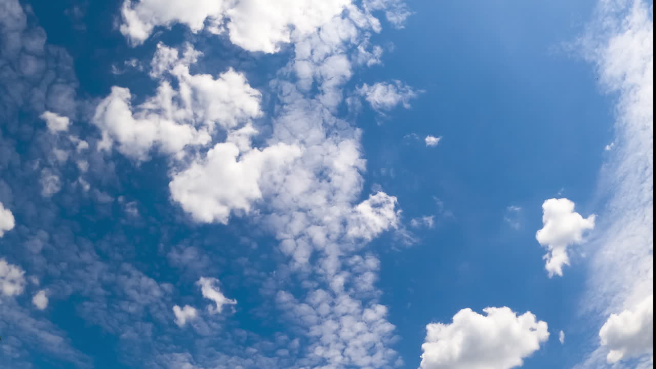 Light airy soft clouds in the beautiful azure sky. Cloudscape moved by the wind in the atmosphere. Low angle view timelapse.