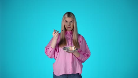una mujer rubia disfrutando de comer un delicioso postre de pastel, retrato de estudio con fondo verde
