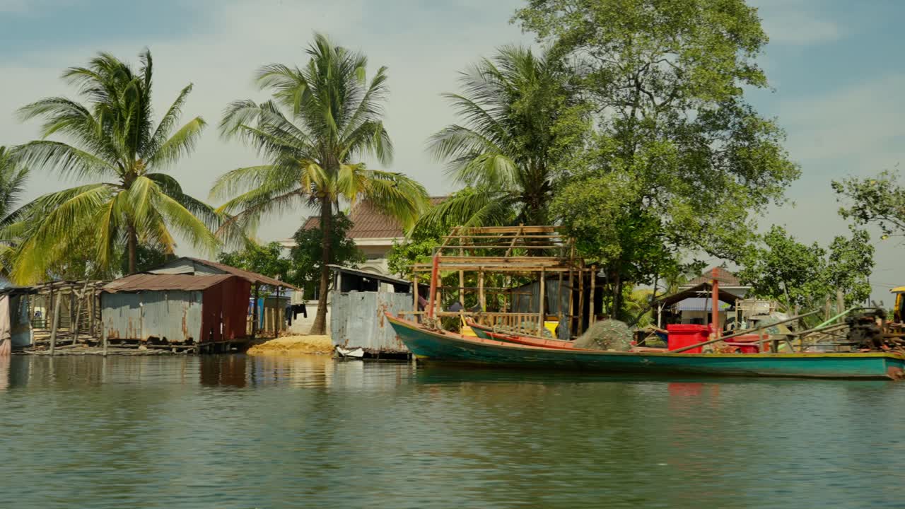 Rustic coastal homes and boats in a poor fishing village next to palm trees