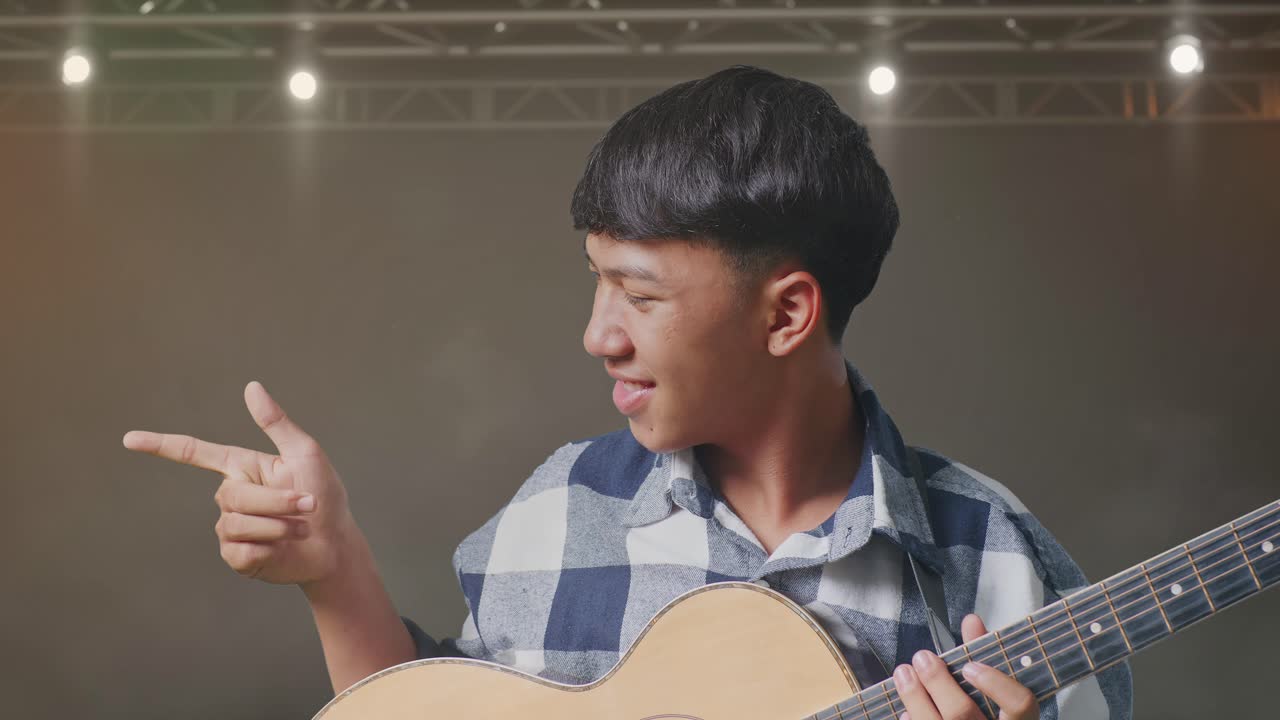 기타를 연주하고 무대에서 을 가리키는 아시아 십대의 클로즈업