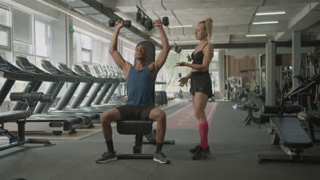 front view of caucasian female monitor and an athletic african american man in the gym.