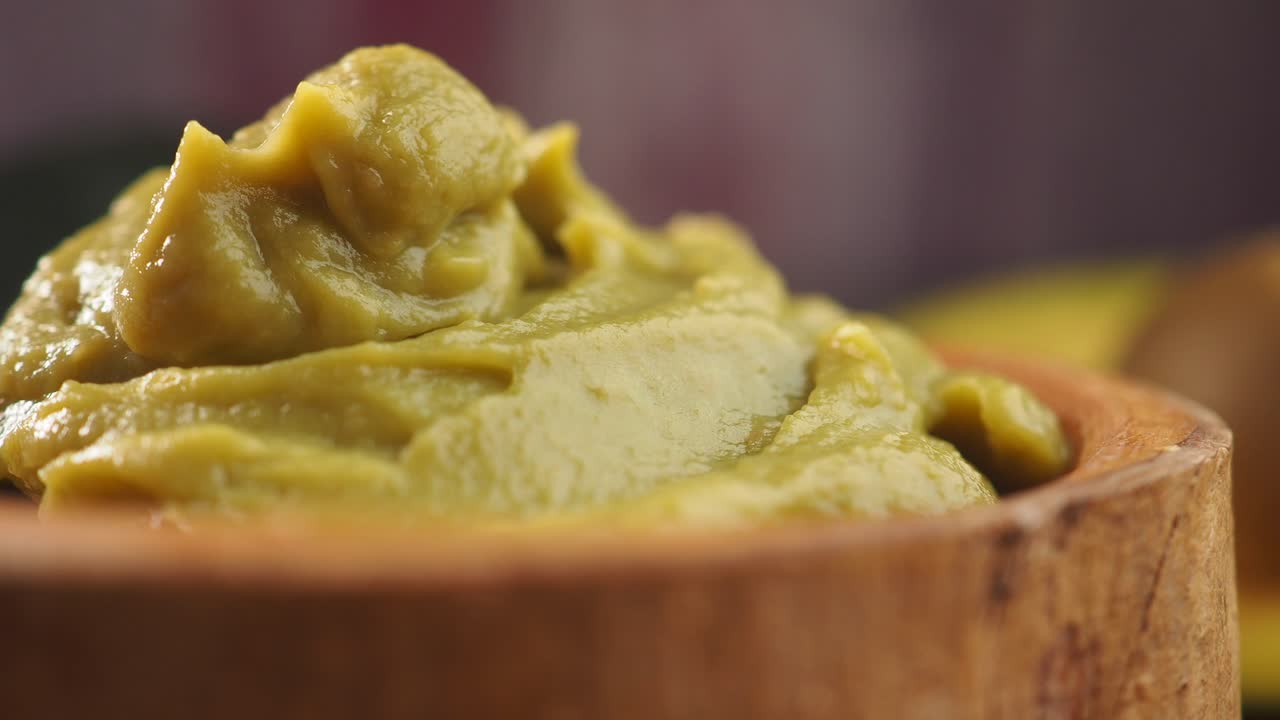 Close-up of Fresh Guacamole in a Wooden Bowl with Avocado