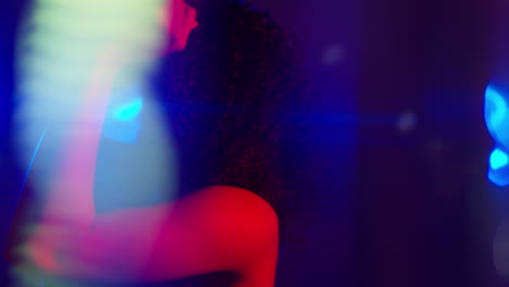 primer plano de una mujer joven en un bar nocturno o discoteca bailando con luces brillantes 4