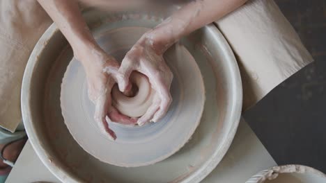 female potter makes a pot on the pottery wheel.