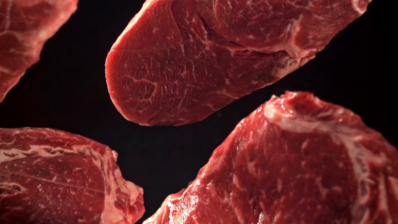 Fresh Raw Beef Steaks Floating on a Black Background