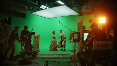 on big film studio professional crew shooting history costume drama movie. on set: director controls cameraman shooting green screen scene with two actors talented wearing renaissance clothes talking