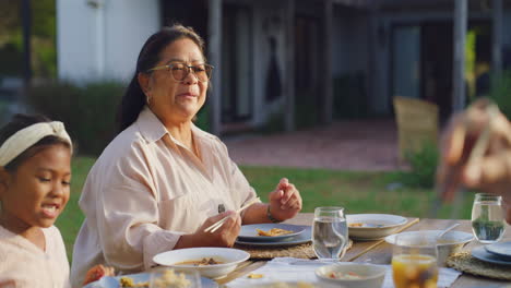 Happy-family-eating-together-at-a-table-outside