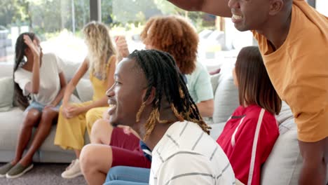 happy diverse friends watching sport on tv and high fiving, slow motion