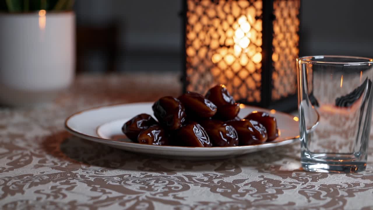 la elegancia y la simplicidad componen una tradicional mesa de iftar con dátiles, una linterna encendida y un vaso de agua, creando una atmósfera cálida y acogedora
