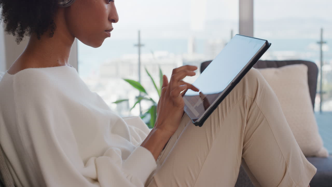 young woman using digital tablet computer relaxing on couch at home browsing online reading emails enjoying sharing comfortable lifestyle on social media