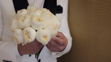 groom holding a bouquet of white flowers