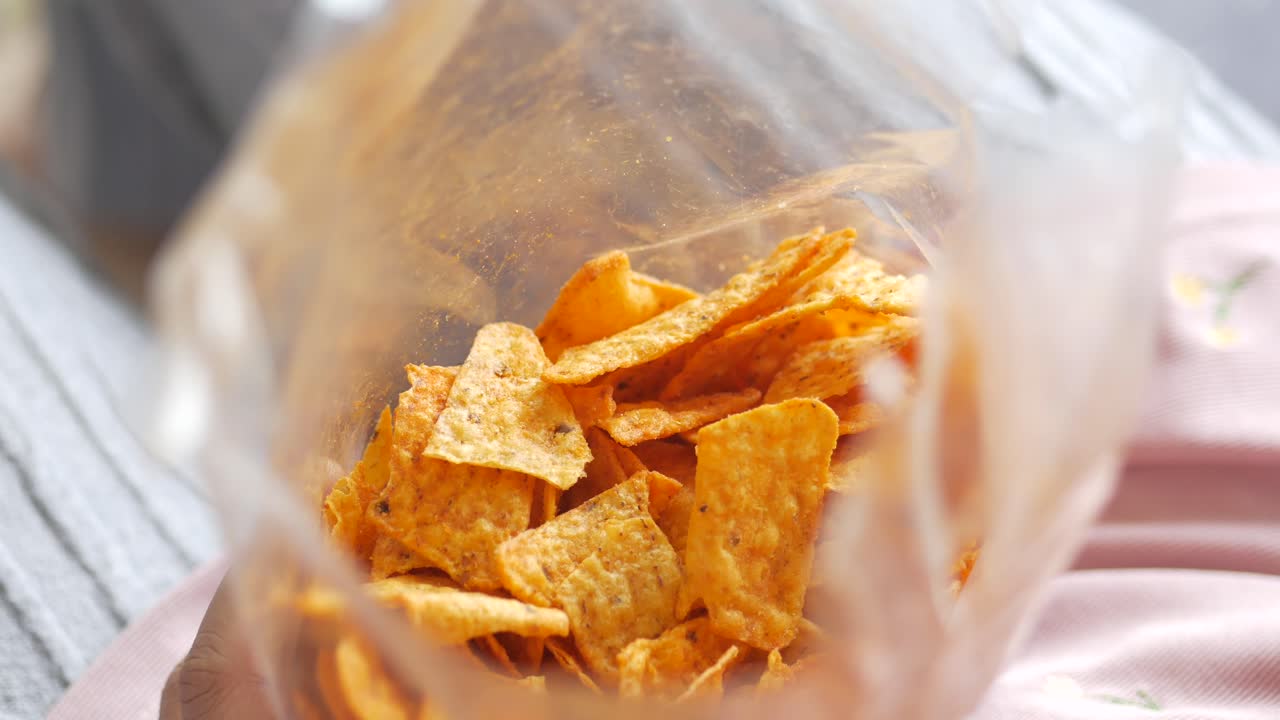 la mano metiendo la mano en una bolsa de papas fritas de tortilla picante