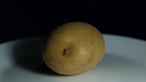 patata en un plato blanco girando hacia la izquierda proyectando sombra, alimento básico, nutrición
