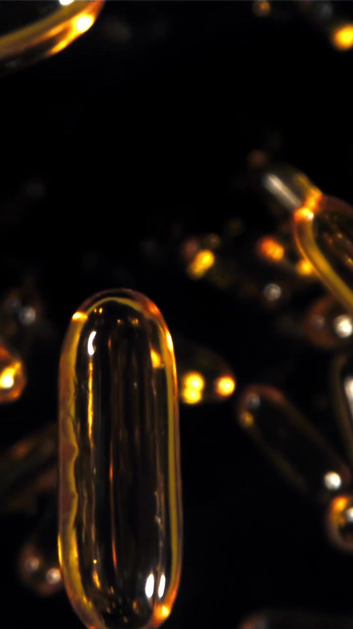 Primo piano di capsule softgel dorate che galleggiano in un liquido scuro