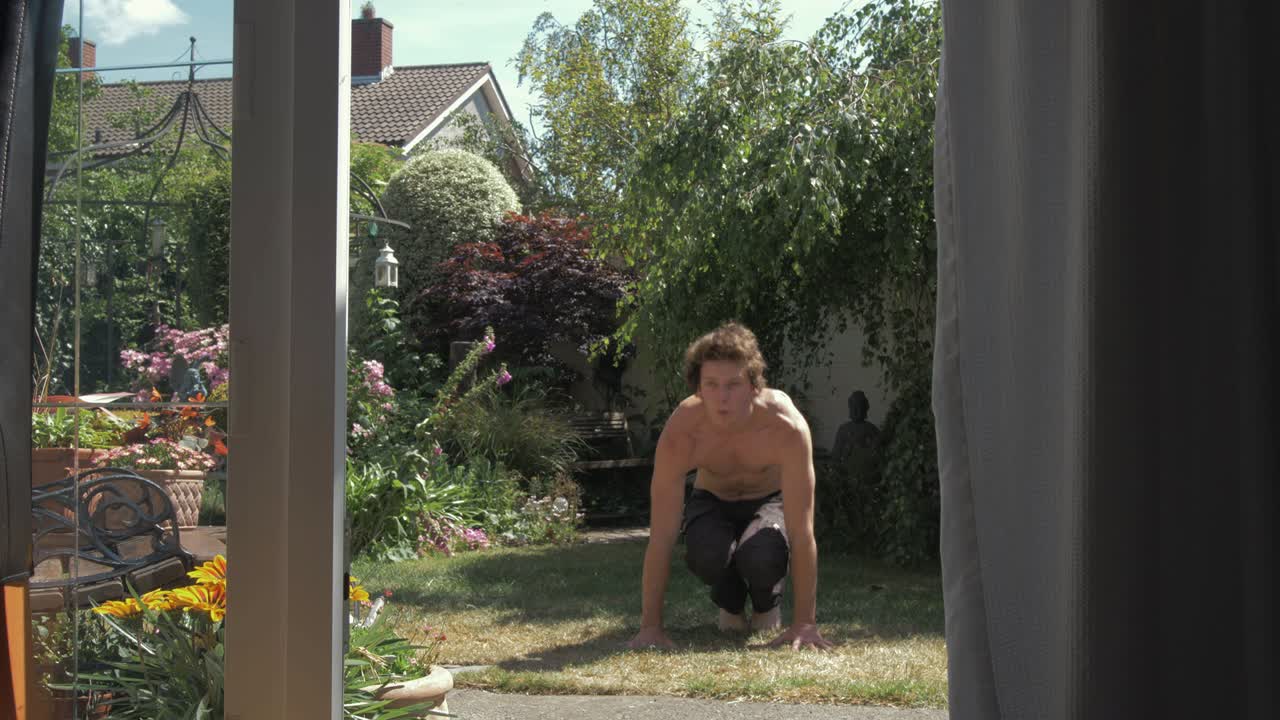 un hombre caucásico topless realiza burpees en el patio trasero