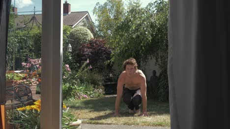 a topless caucasian man performs burpees in backyard