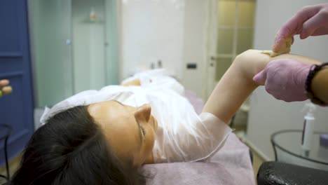 Woman getting arm waxing treatment at a spa