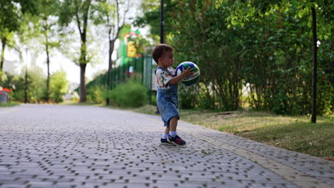 lovely happy toddler runs with a ball carrying a ball. baby having fun time in the park in summer.