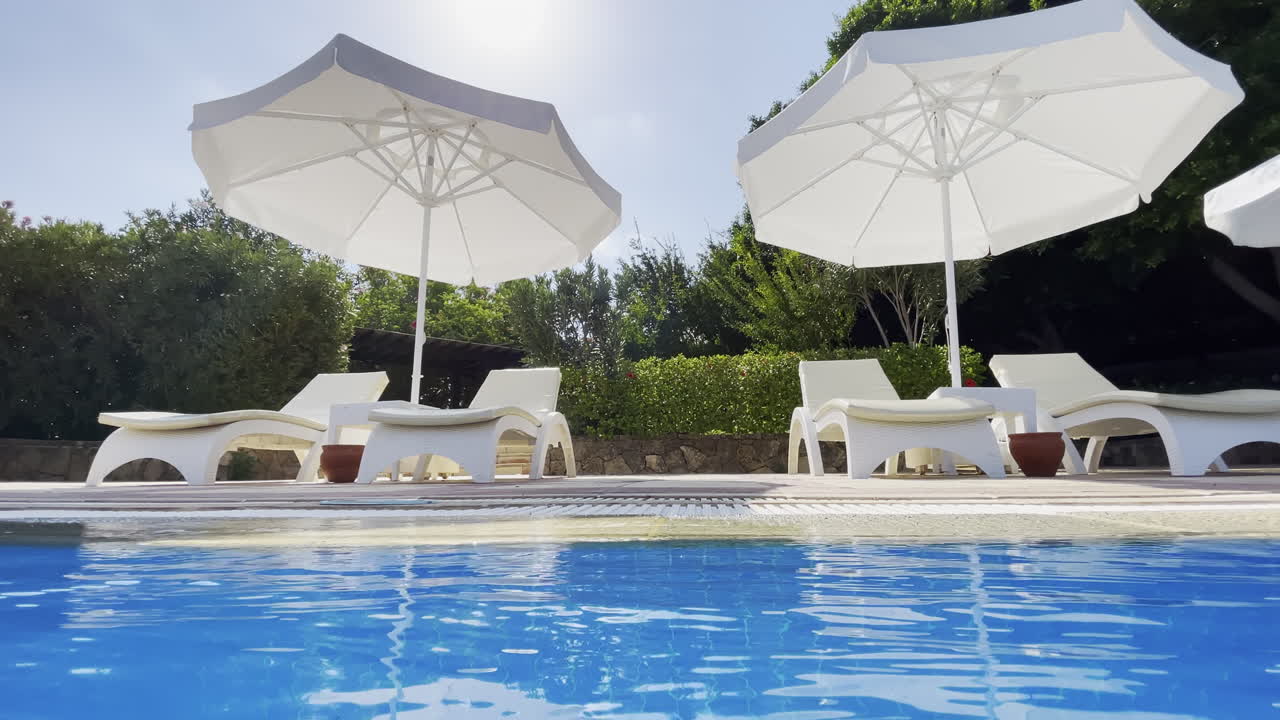 Veduta grandangolare dalla piscina verso i lettini vuoti.