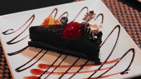 chocolate cake with strawberry and wip cream on a white plate at a fancy restaurant table