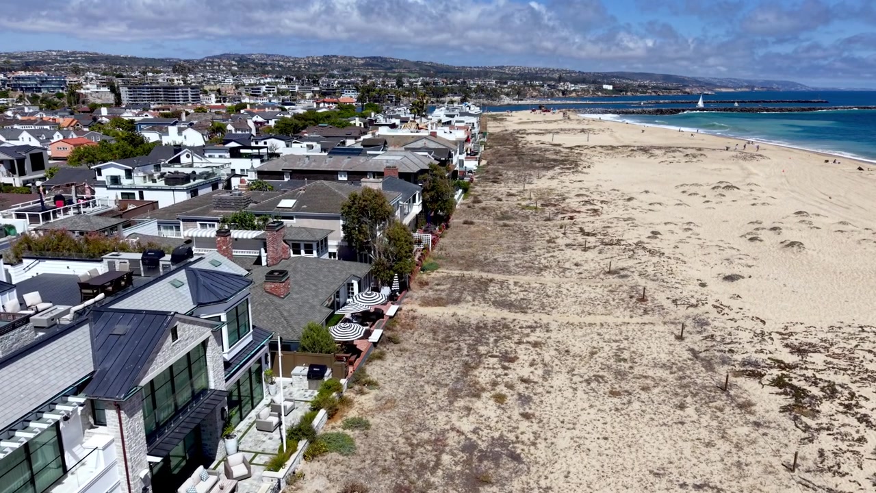 Toma aérea lenta a lo largo de las casas frente a la playa en Newport Beach, California.