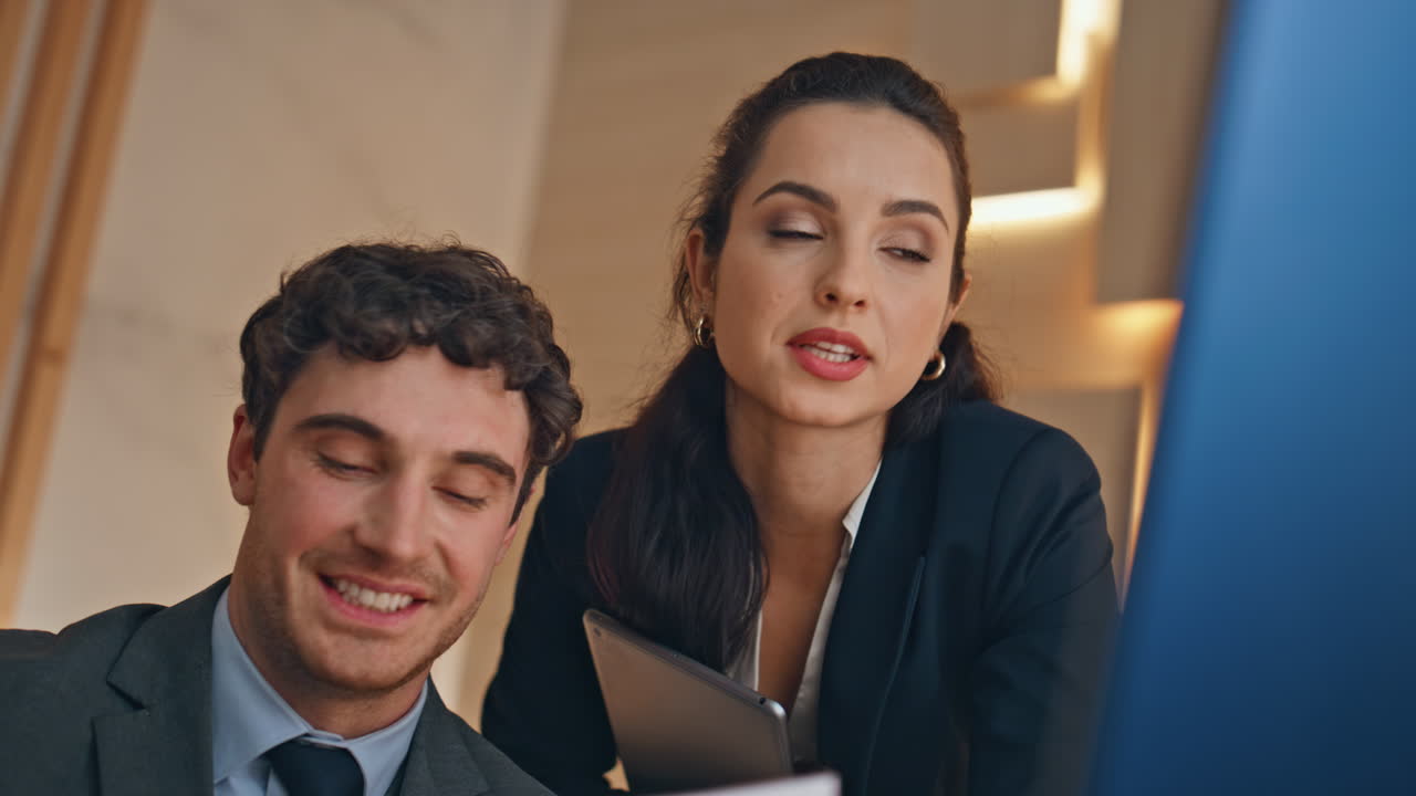 Primer plano de interior con dueños de negocios hablando frente a un monitor. Pareja en videollamada.