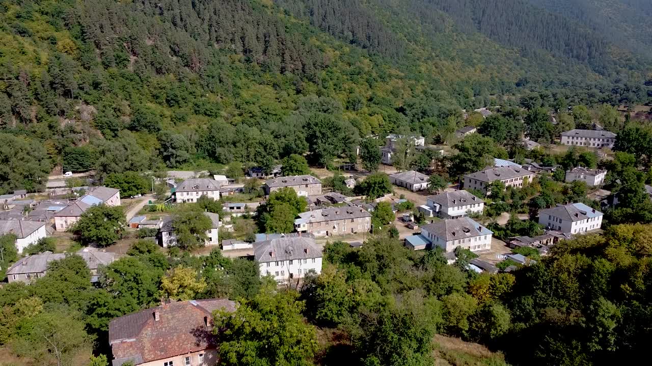 Nestled in the mountains, this charming village showcases rustic buildings and lush greenery. The picturesque landscape captures the tranquil essence of rural life in the fall