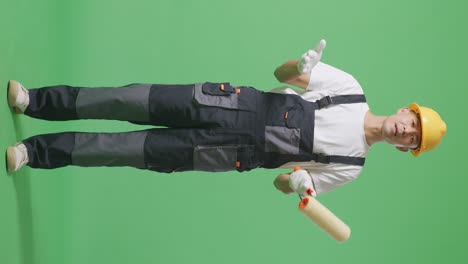full body of wondering asian man painter wearing safety helmet saying why and standing doubtfully in the green screen background studio
