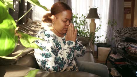 african american lady praying with joy in sunroom of her home