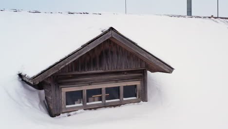 attic windows on snowy roof of house during winter